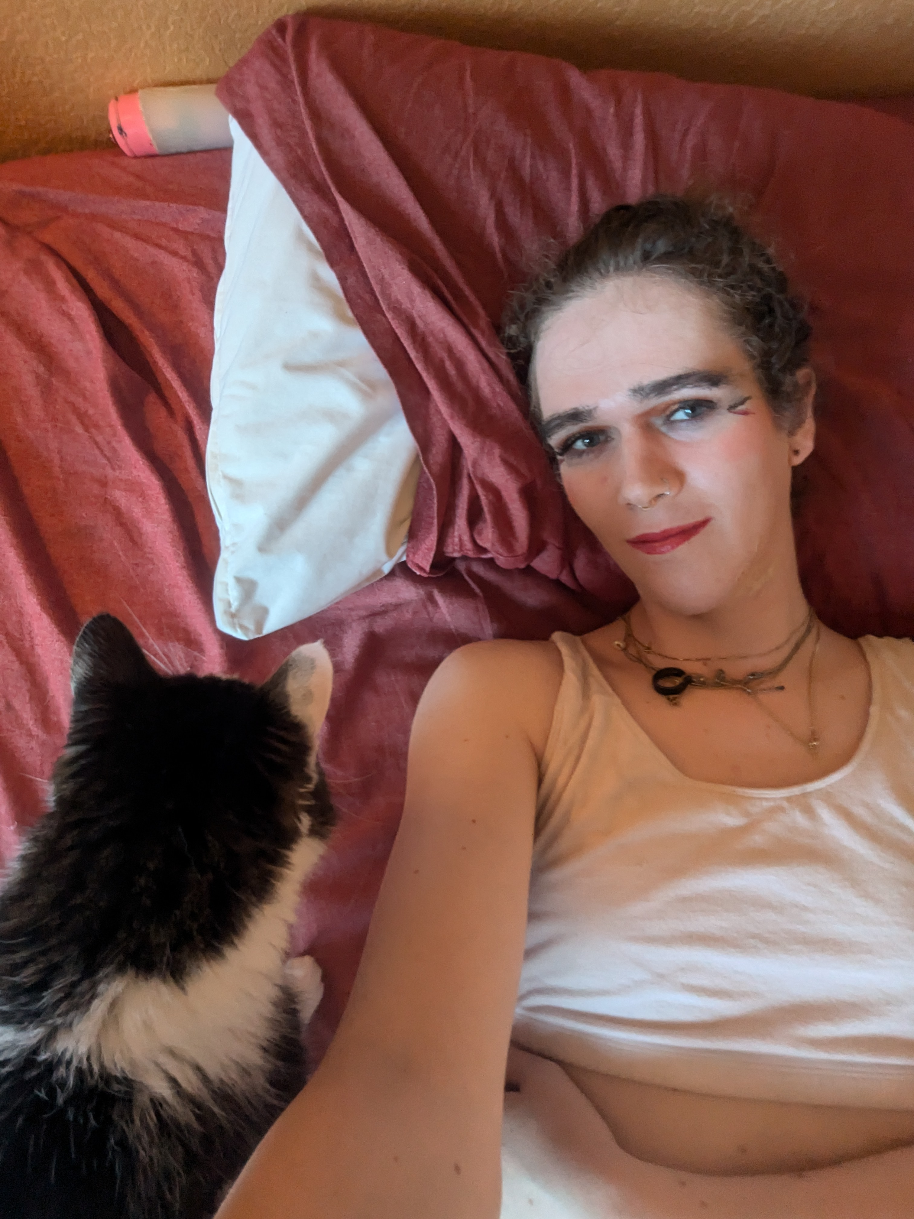 The photo shows a woman lying on a bed with a red blanket and... - by Daisy