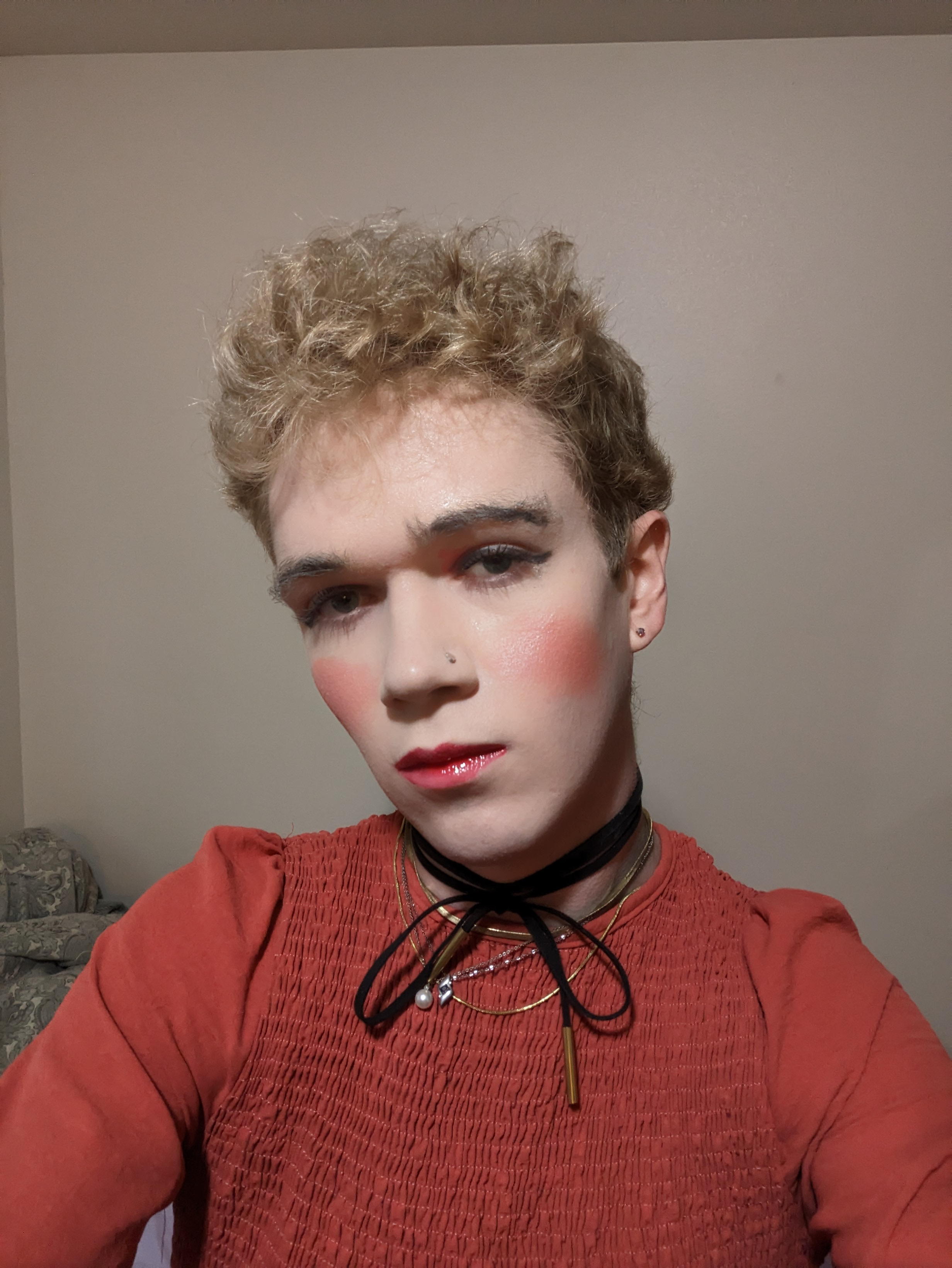 The photo shows a woman taking a selfie indoors against a plain... - by Daisy