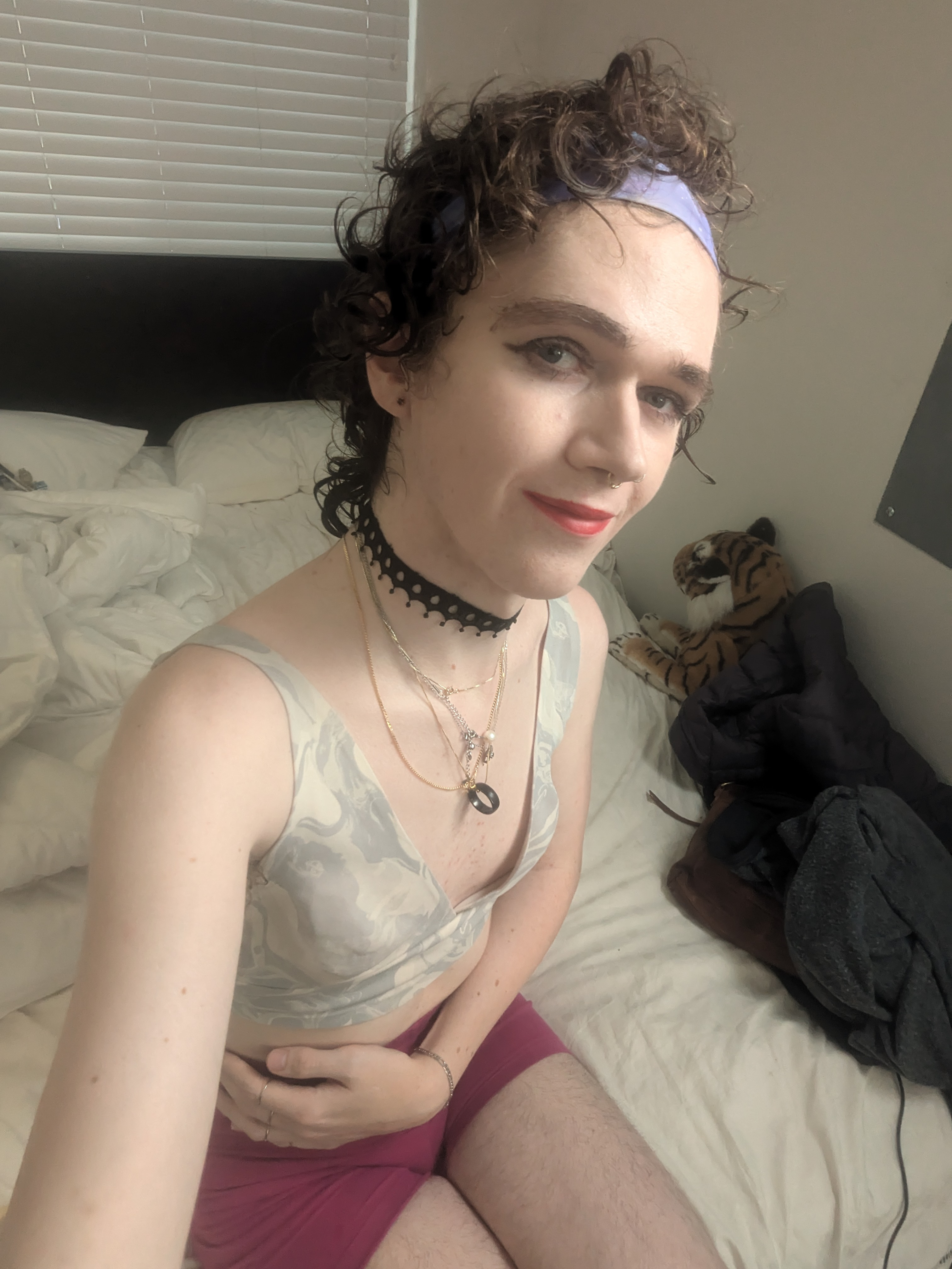 The photo shows a woman sitting on a bed in a bedroom. She has... - by Daisy