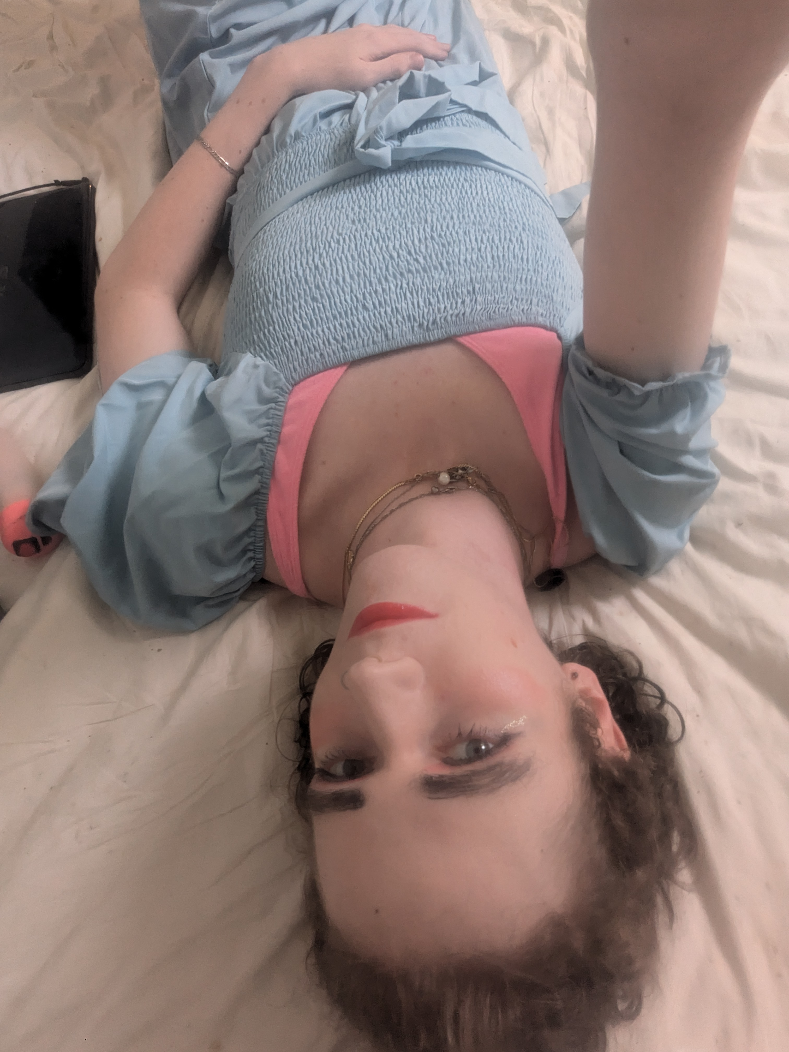 This photo shows a woman lying on a bed, taking a selfie from an... - by Daisy