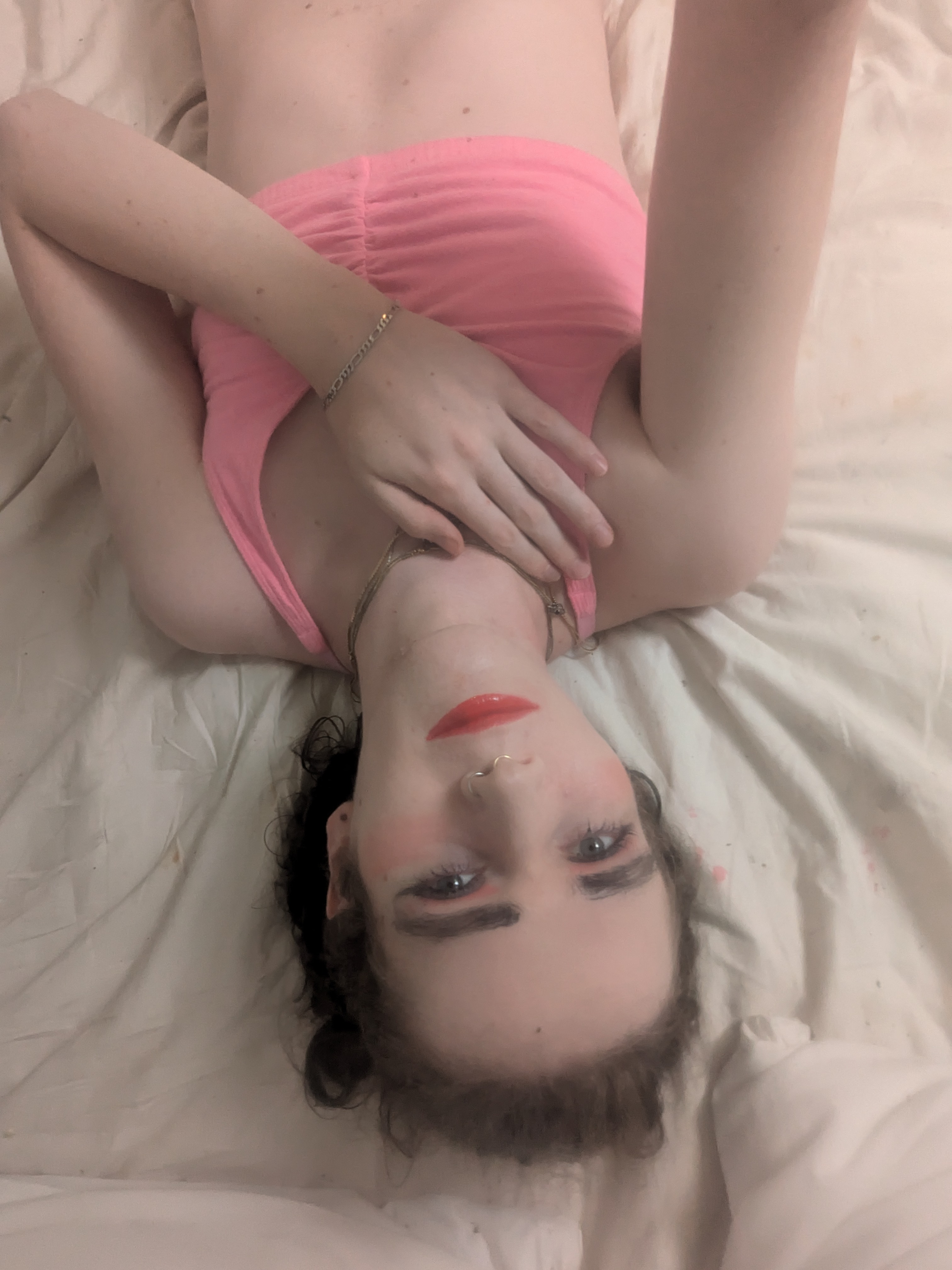 The photo shows a woman lying down on a light-colored bed sheet,... - by Daisy