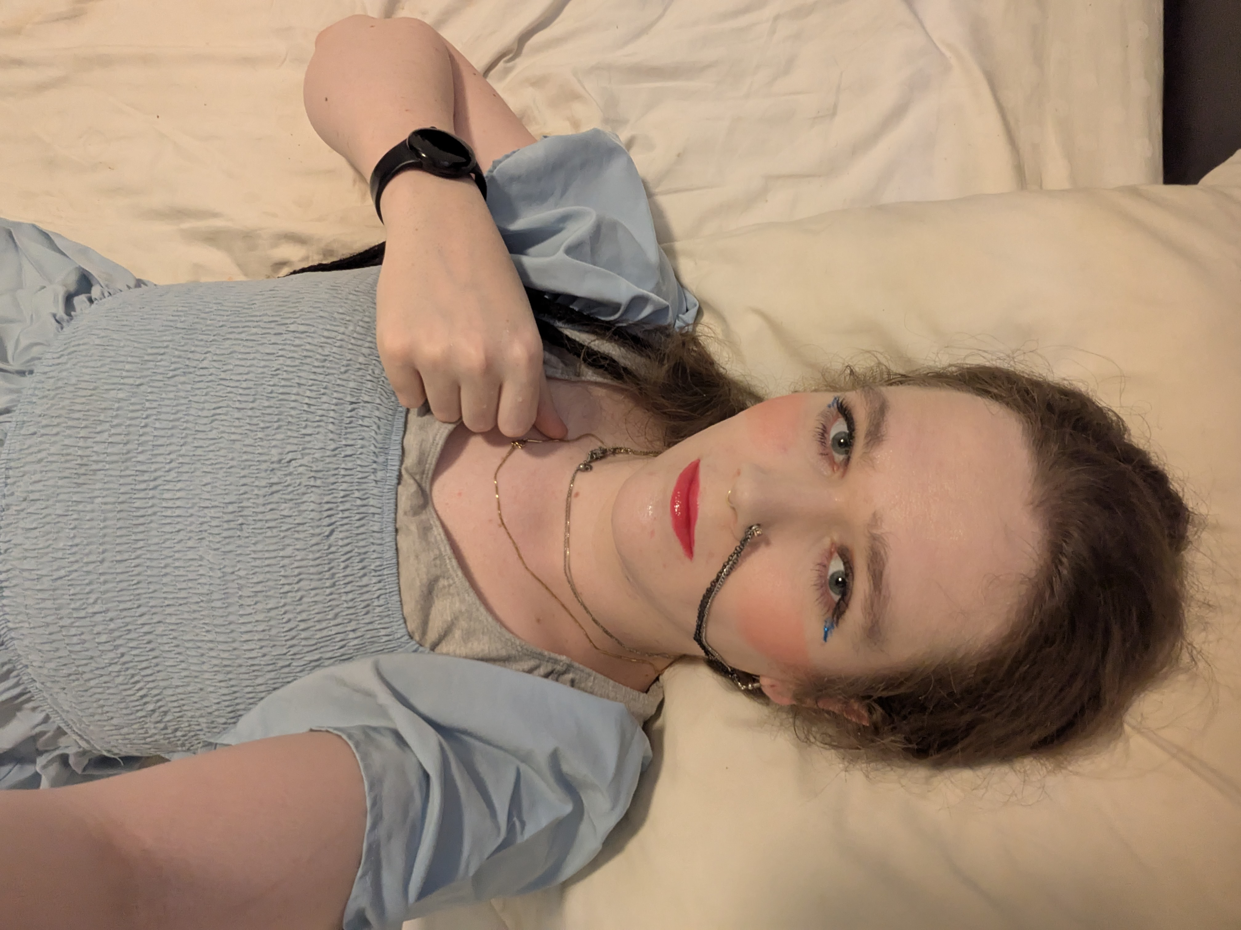 The photo shows a woman lying on a bed or a soft surface. She has...
