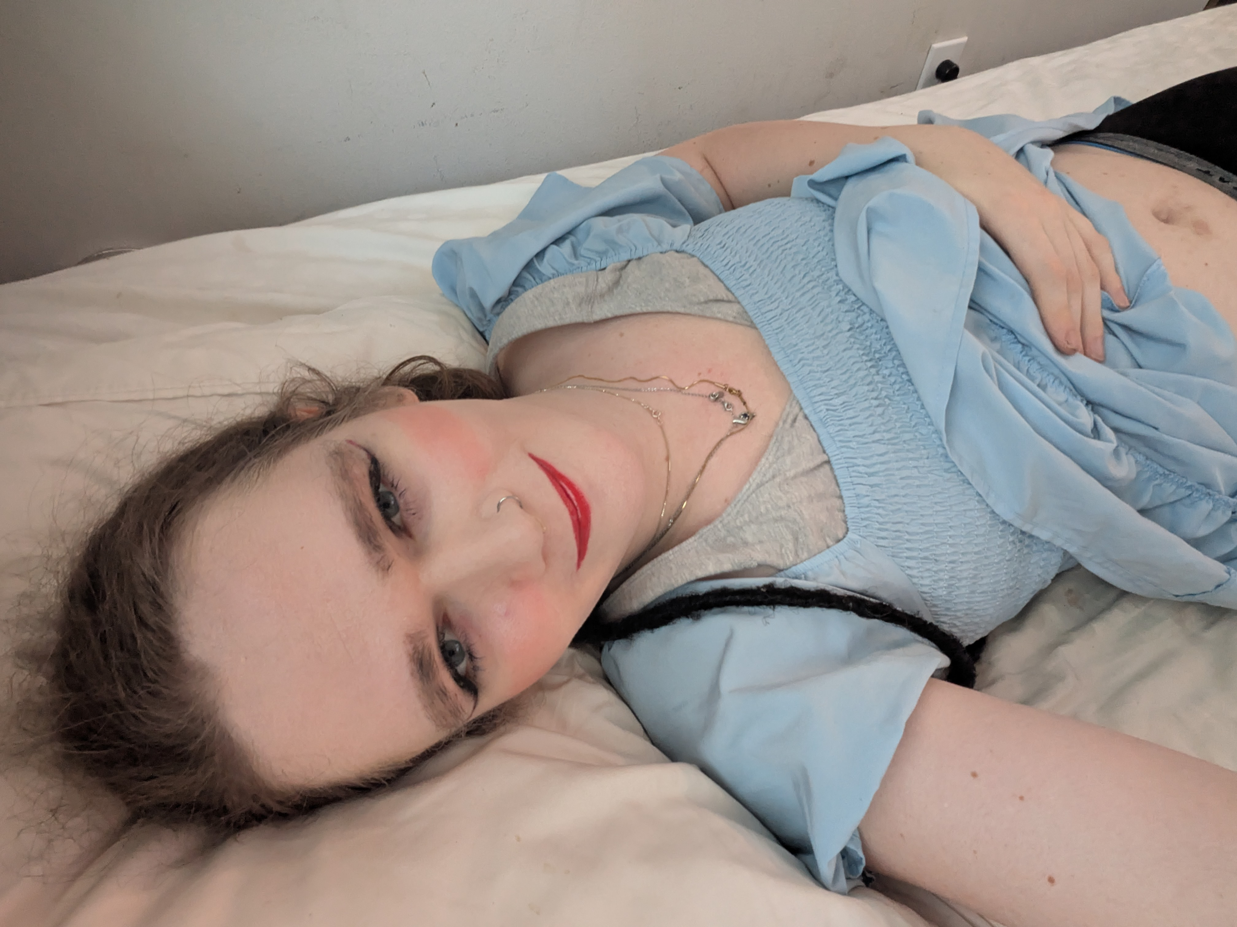'N Vrou wat met 'n rooi kombers op 'n bed lê.