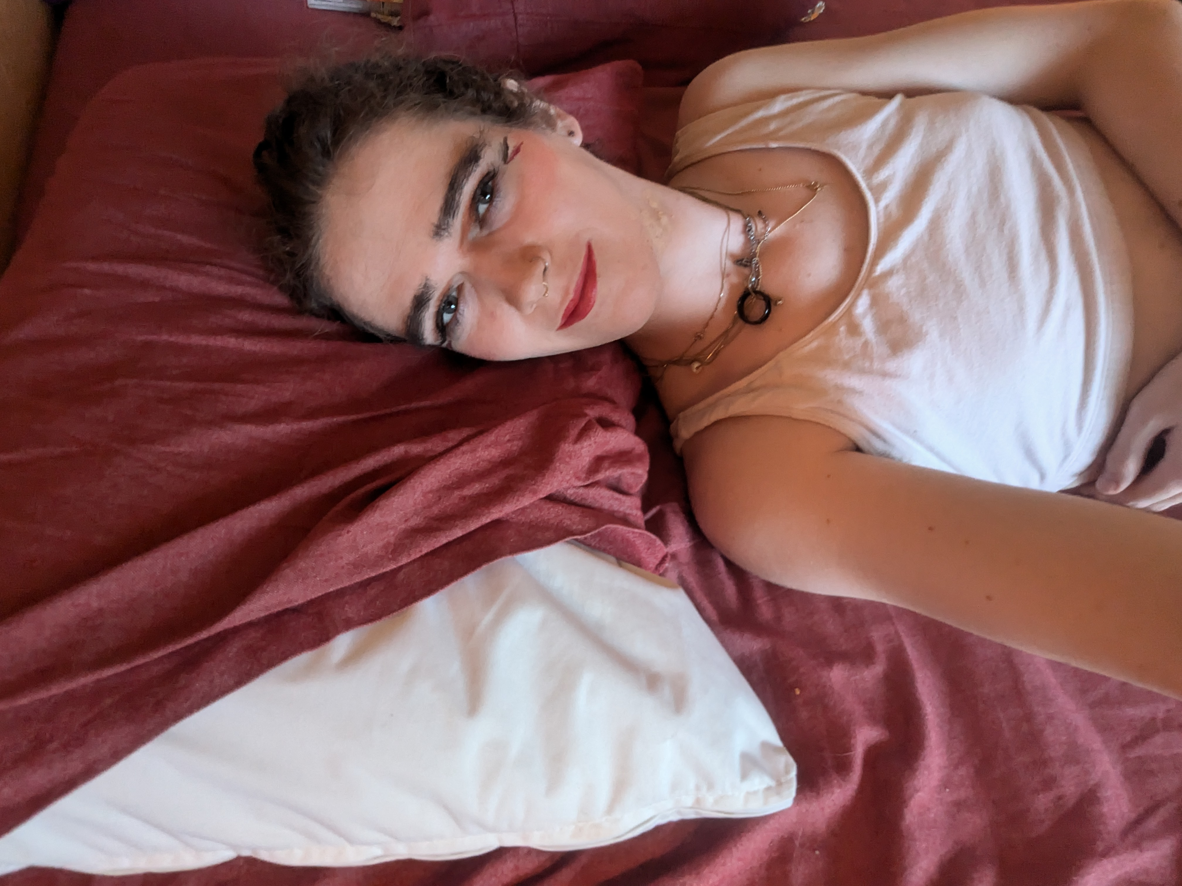 This photo shows a woman lying down on a bed with a reddish... - by Daisy