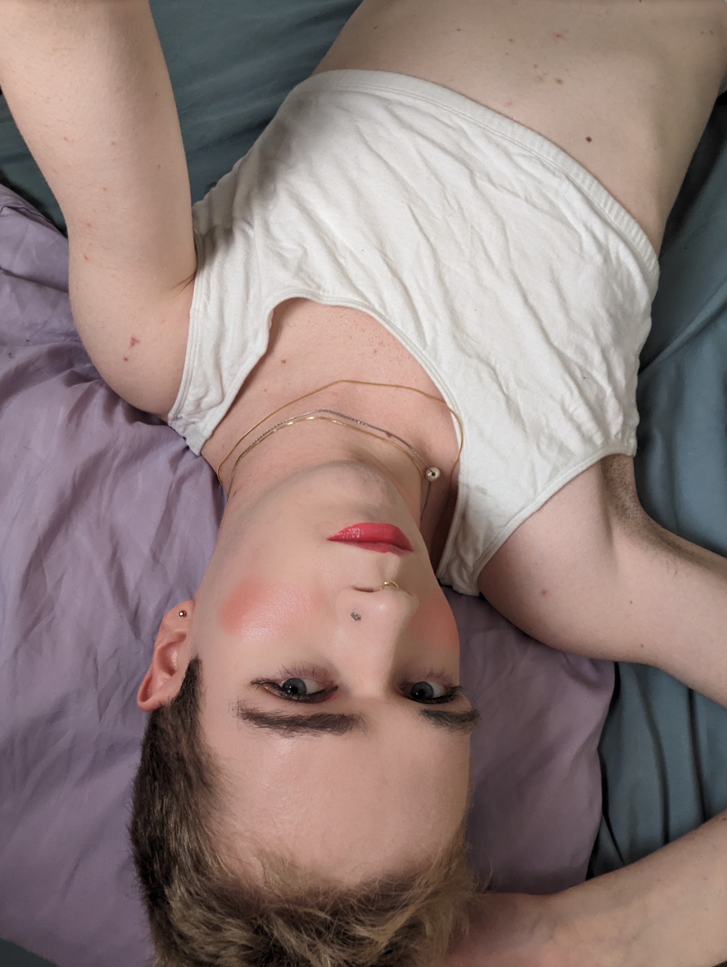 This photo shows a woman lying down on a bed with a purple pillow... - by Daisy