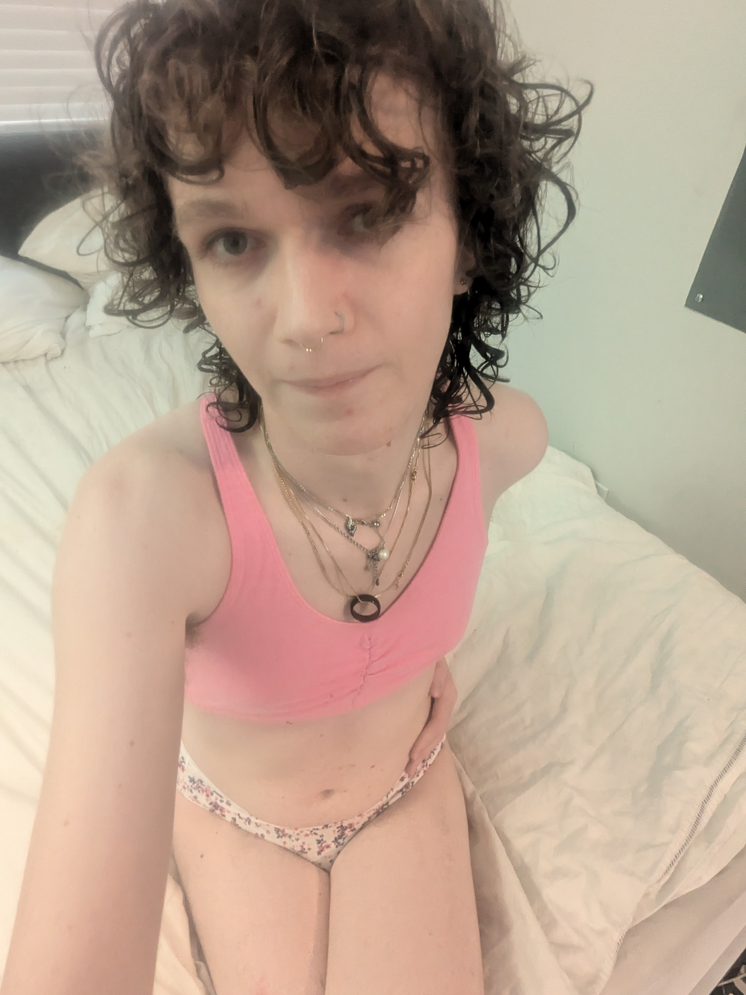 The photo shows a woman with curly hair sitting on a bed in a... - by Daisy