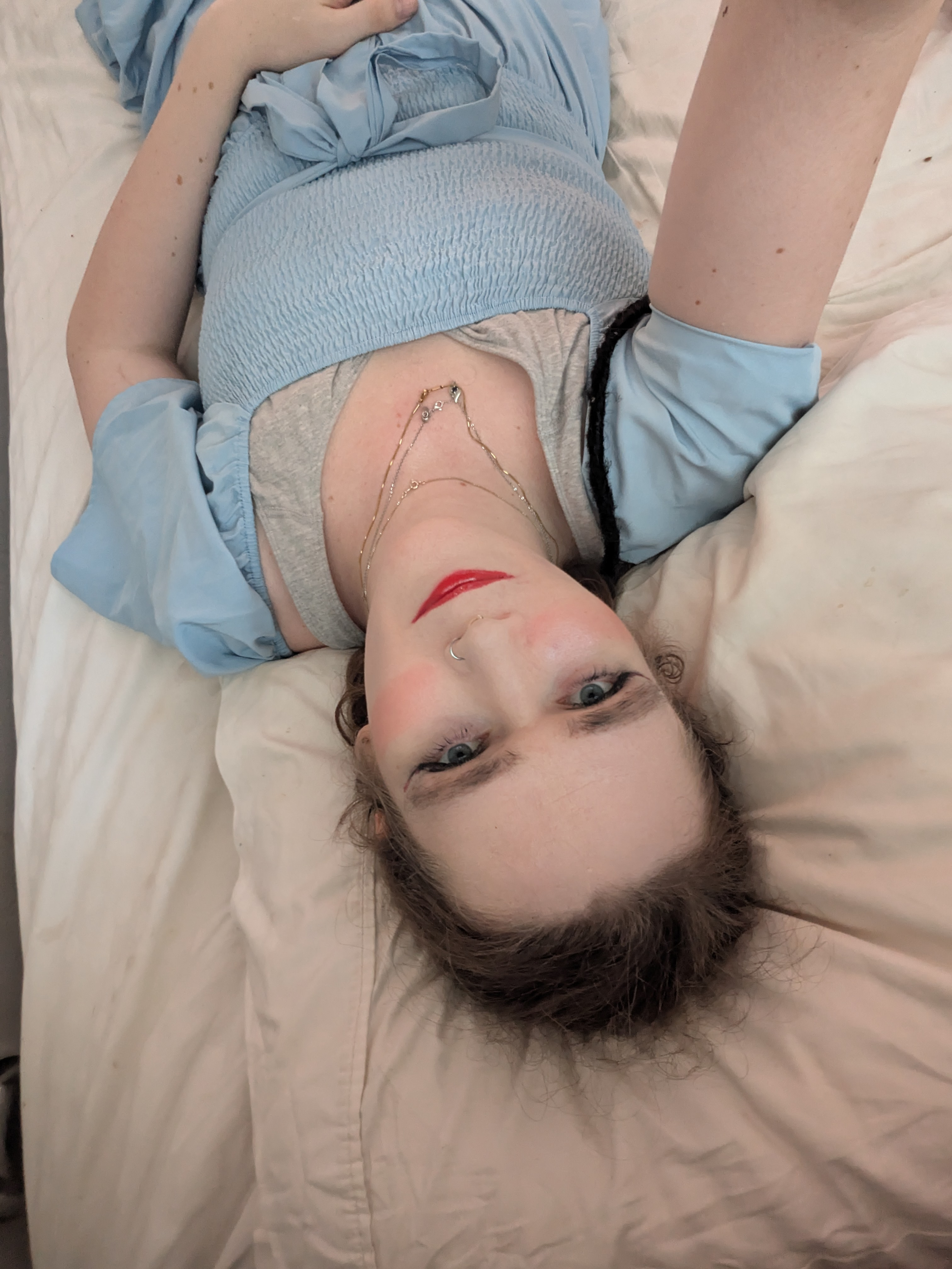 'N Vrou wat met 'n rooi kombers op 'n bed lê.