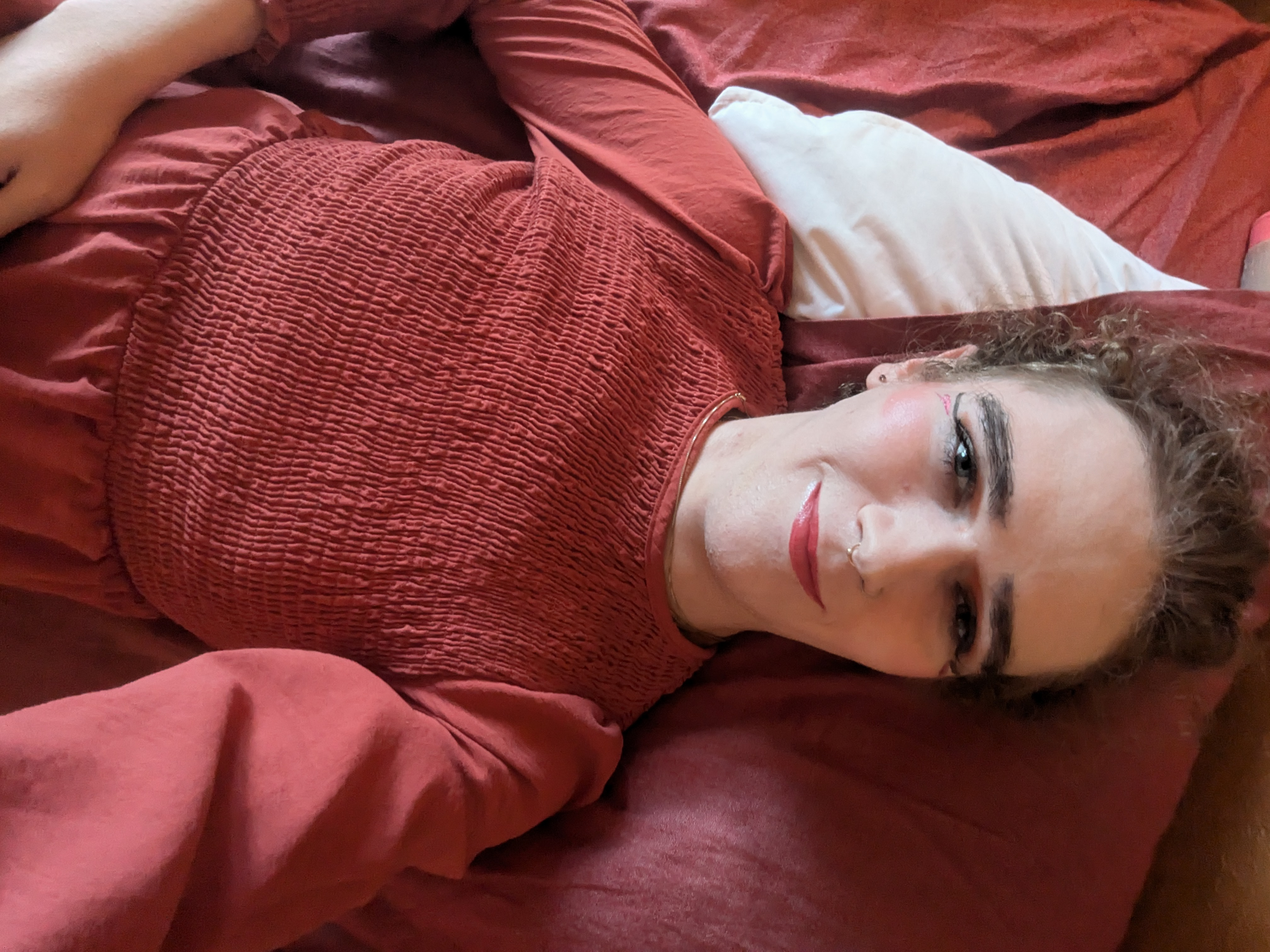 The photo shows a woman lying down on a bed or couch. She is... - by Daisy