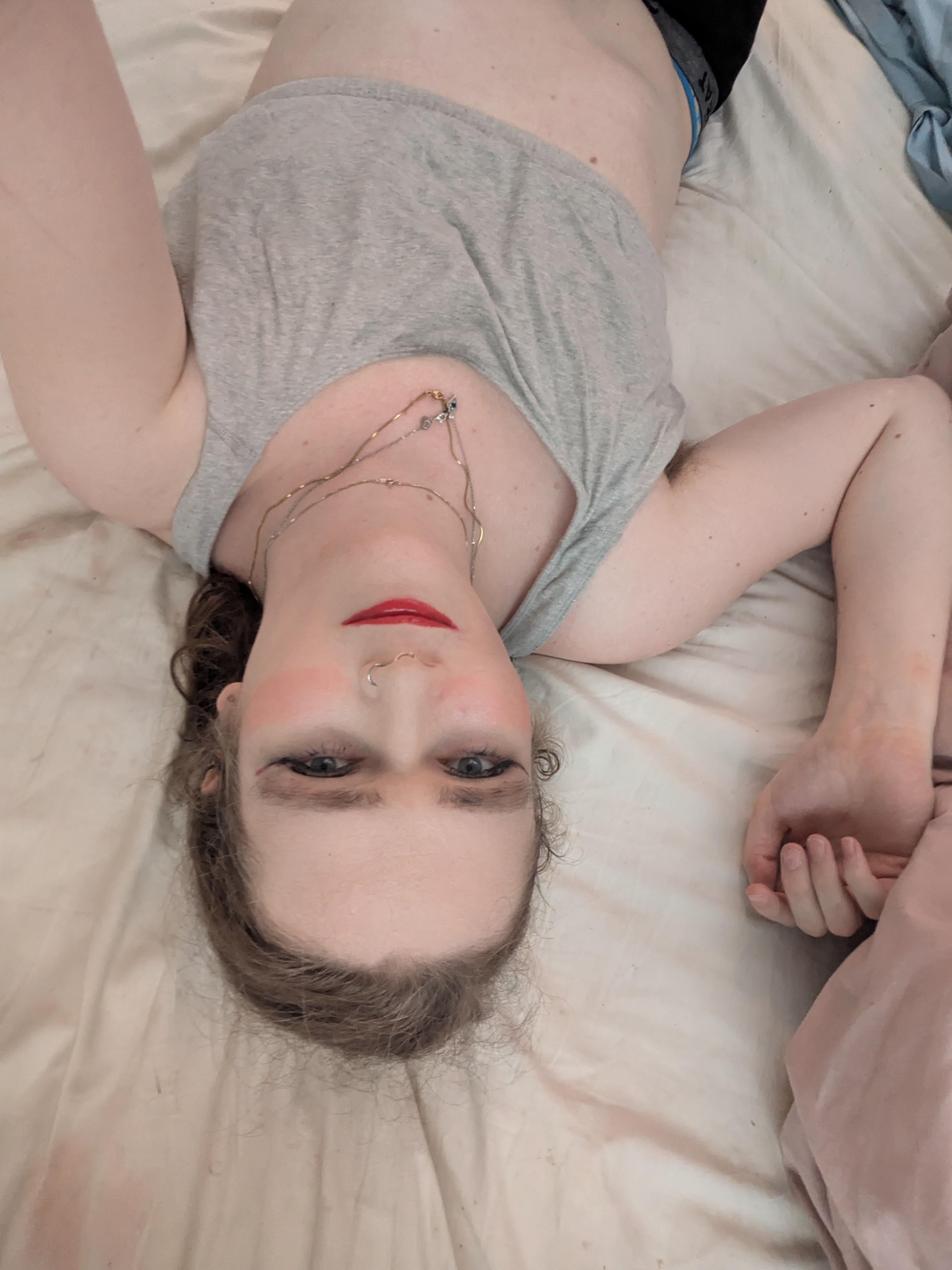 'N Vrou wat met 'n rooi kombers op 'n bed lê.