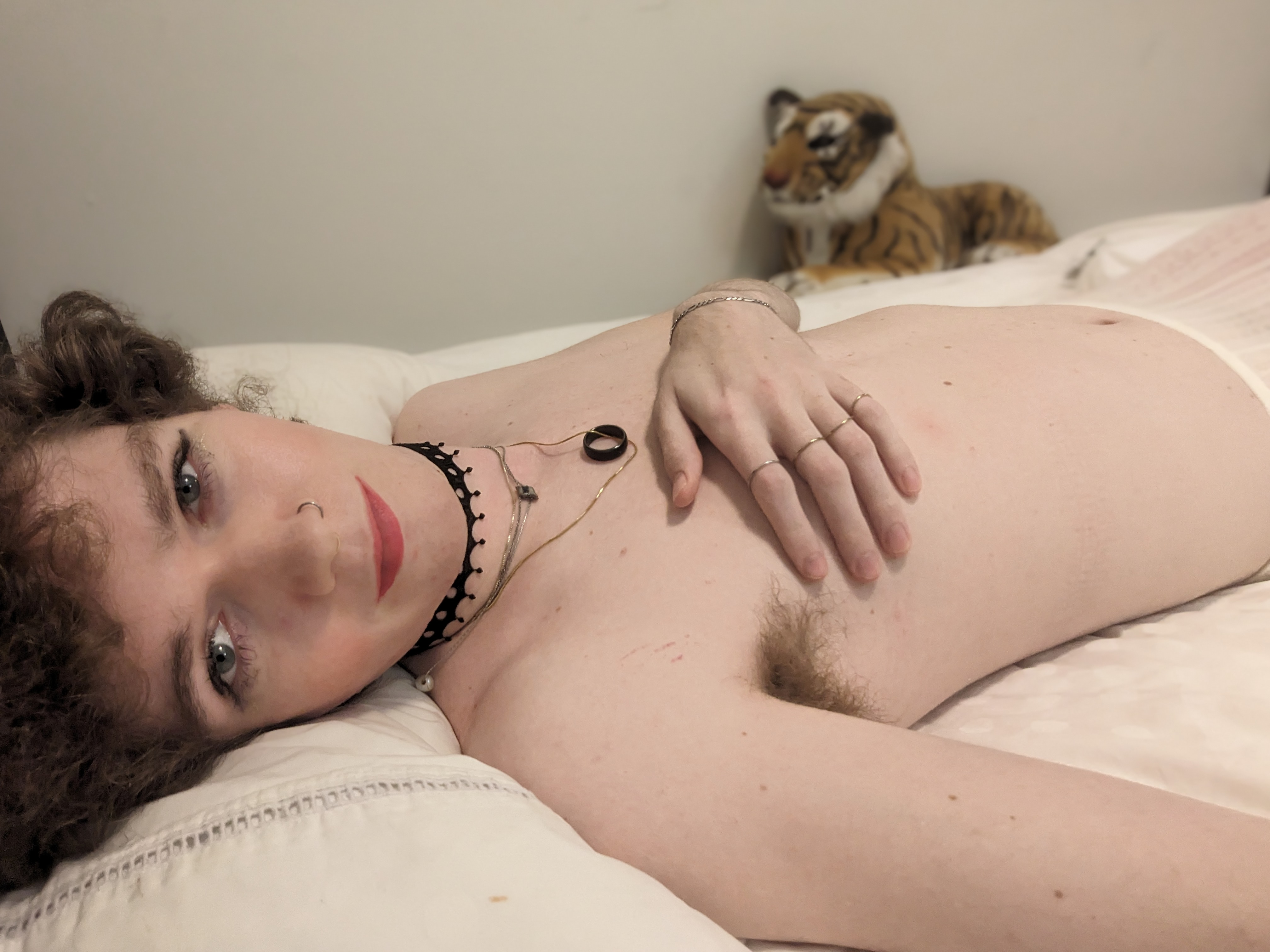 The image shows a woman lying on a bed with white sheets. The... - by Daisy