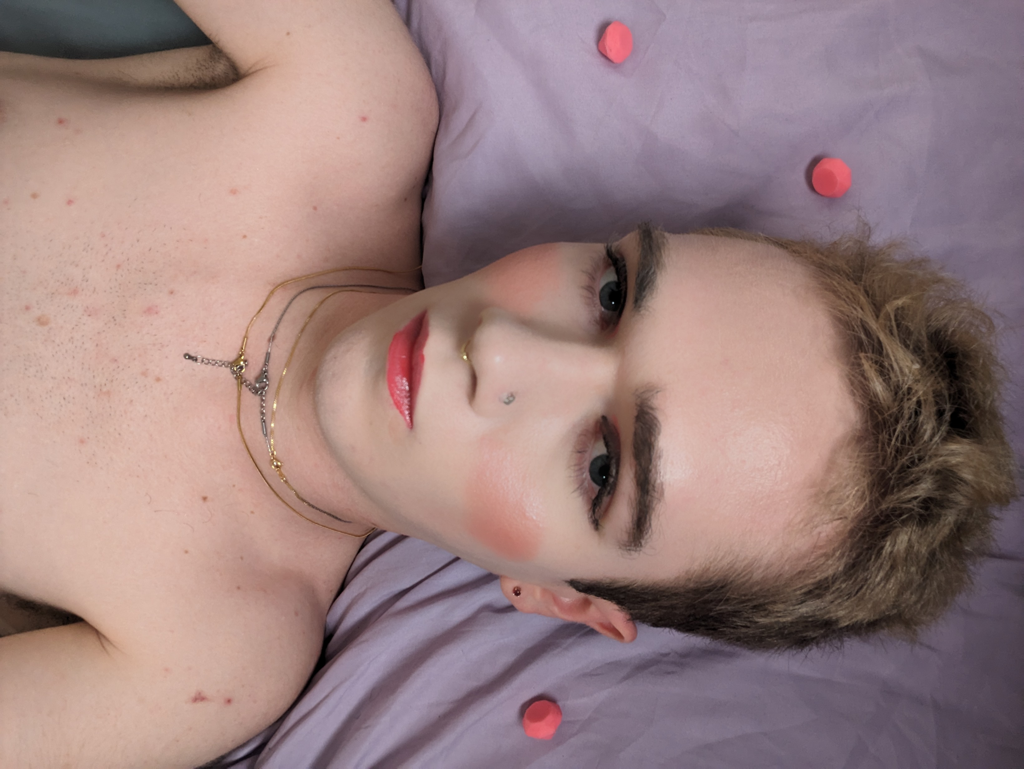 The photo shows a woman lying on a purple surface, possibly a bed.... - by Daisy