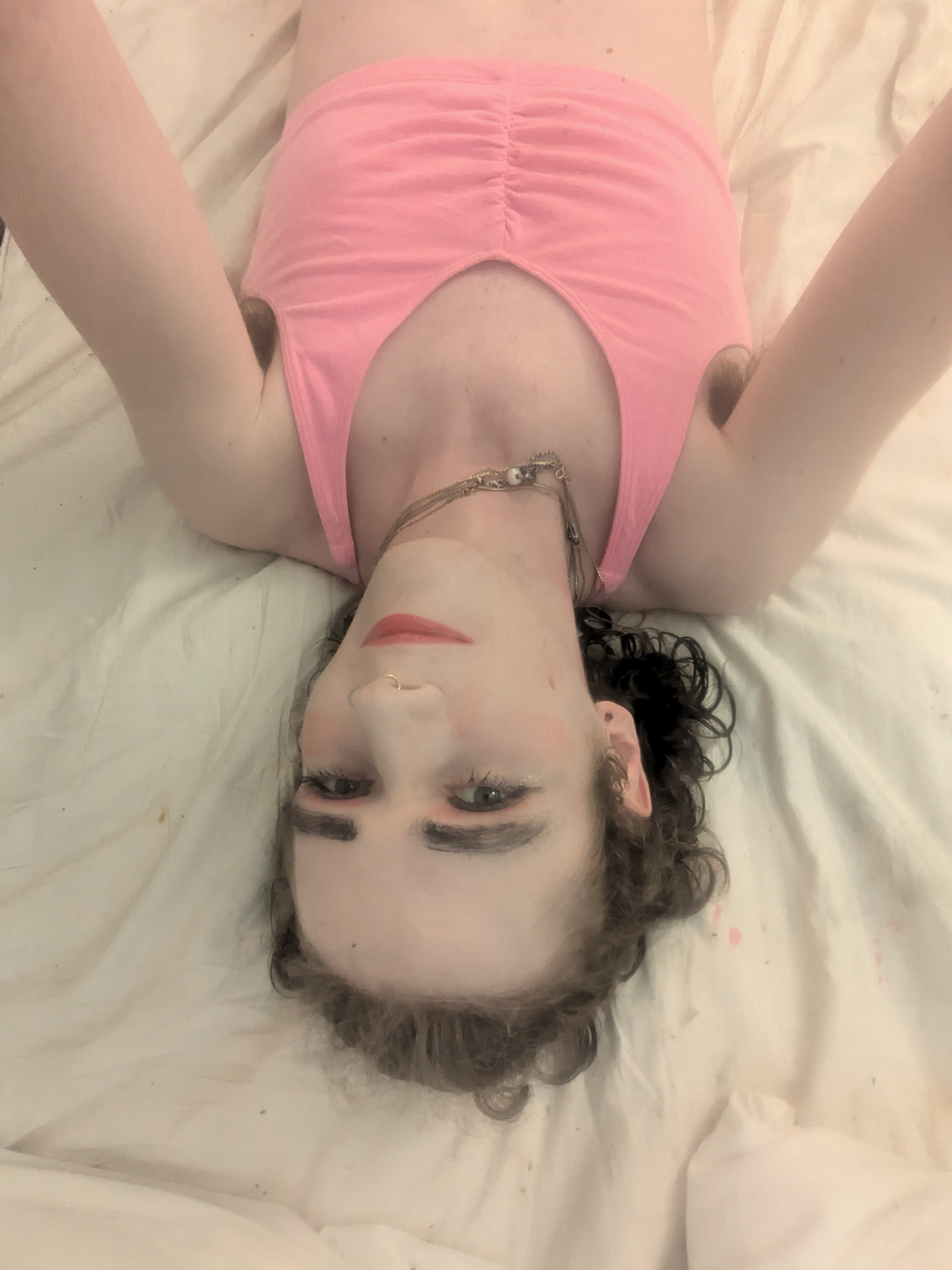 The photo shows a woman lying down on a bed. She is wearing a pink... - by Daisy