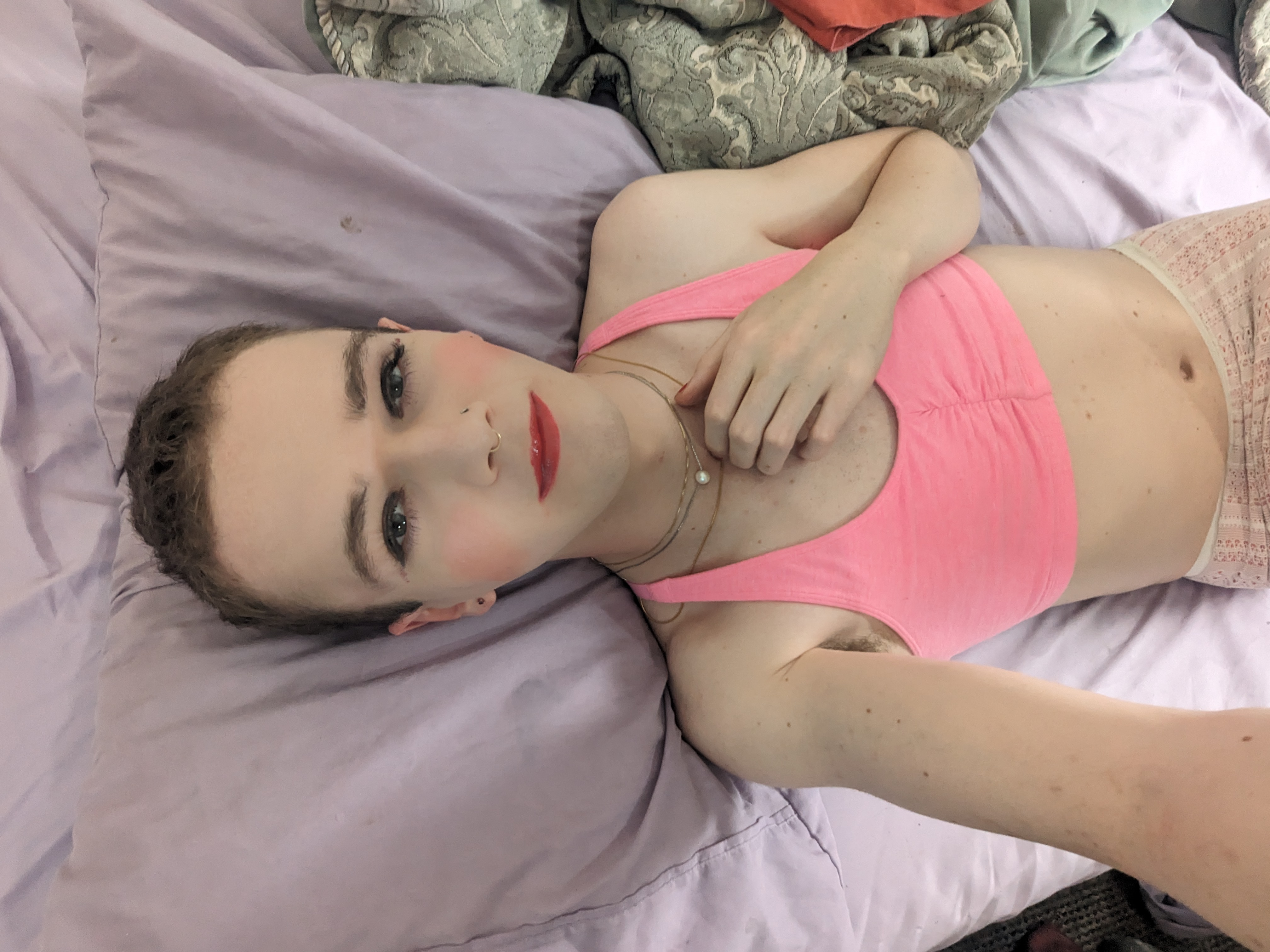 A woman laying on a bed with a pink shirt. - 经过 Daisy